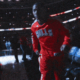 a man wearing a red bulls jersey is raising his arms
