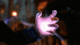 a person 's hand is reaching out towards a light