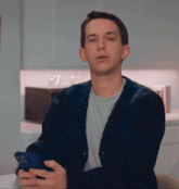 a man in a blue cardigan holds a cell phone