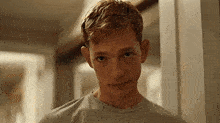 a young man with red hair is looking at the camera in a room .