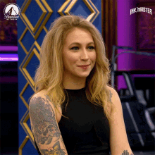 a woman with a tattoo on her arm is smiling in front of a paramount network logo