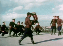 a group of men in military uniforms are dancing in a field