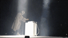a person in a white coat is standing in front of a white box on a stage