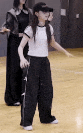 a woman in a white shirt and black pants is dancing on a wooden floor in a dance studio .