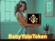 a woman is holding a tv with a picture of a dog on it and the words baby yolo token behind her