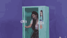 a woman is standing in front of a blue cabinet and waving .