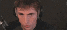 a man wearing headphones and a black shirt looks at the camera