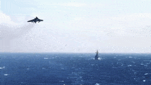 a fighter jet is flying over the ocean with a ship in the distance