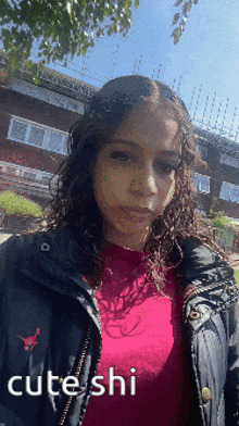a girl wearing a red shirt and a black jacket with cute shi written on the back