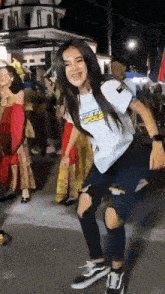 a woman wearing a white shirt and ripped jeans is dancing in a crowd .