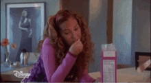 a woman in a purple shirt is sitting at a table eating cereal .