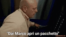 a bald man in a suit says " dai marco apri un pachetto "