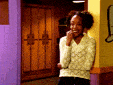 a woman in a white sweater is smiling in a hallway with lockers in the background