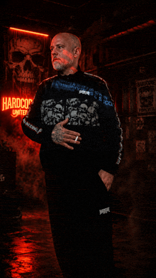 a man stands in front of a sign that says hardcore united