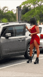 a woman in a red dress standing next to a jeep