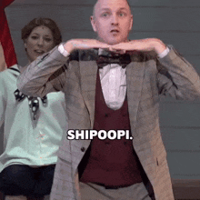a man in a suit and bow tie is making a gesture with his hands .