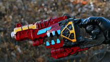 a person is holding a red and yellow toy gun with a yellow triangle on it