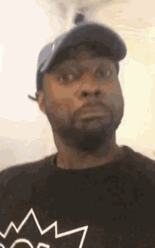 a man with a beard wearing a hat and a black shirt .