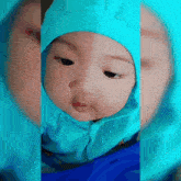 a baby wearing a blue hooded jacket and a blue hijab