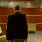 a man in a black jacket is walking in a room