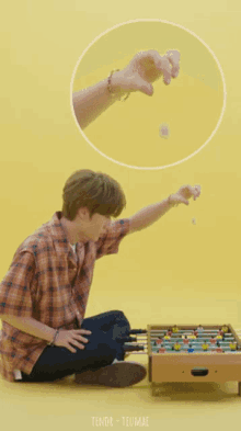 a man in a plaid shirt sits on the floor playing a game