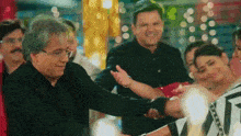 a man is holding a woman 's hand while a group of people are dancing in a room .