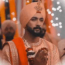 a man with a beard wearing a turban is praying with his hands folded
