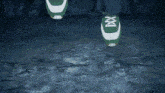 a person wearing a pair of green and white tennis shoes