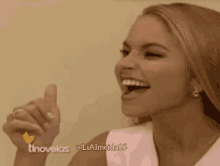 a woman is smiling and giving a thumbs up in front of a screen that says tnovelas