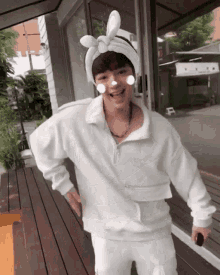 a man wearing a headband with bunny ears is standing on a wooden deck
