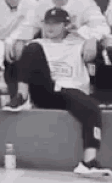 a man in a baseball cap is sitting on a ledge .