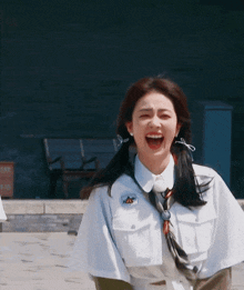 a woman wearing a white shirt and tie is laughing with her mouth open