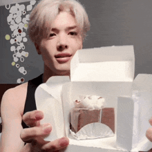 a man is holding a box with a piece of cake inside of it
