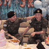 two men in military uniforms are sitting on a couch and one has the number 8 on his sleeve
