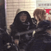 a woman in a hooded jacket stands in front of a sign that says ' chinese ' on it