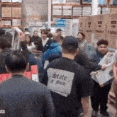 a man wearing a black shirt that says state of mind is standing in a crowd of people .