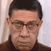 a man wearing glasses and a turtleneck is making a funny face .