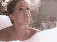 a woman is taking a bath in a tub filled with foam .