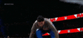 a man without a shirt is jumping in the air in a wrestling ring