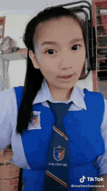 a girl in a school uniform with a tie is taking a selfie .