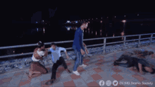 a man in a blue jacket is walking across a bridge at night .
