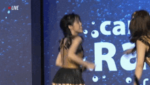 two women are dancing in front of a coca cola logo