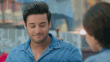 a man in a denim shirt is smiling and looking at a woman