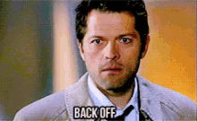 a man in a suit and tie has the word back off on his face
