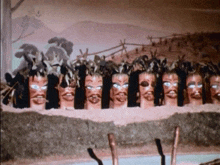 a row of wooden faces with feathers on their heads