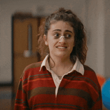 a woman wearing a red and brown striped sweater has a nose ring on her nose