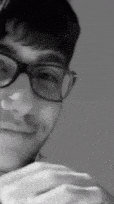 a black and white photo of a man wearing glasses and smiling .