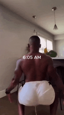 a man without a shirt is squatting down with the time of 6:05 am