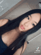 a girl with long black hair is taking a selfie with a tiktok watermark