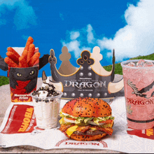 a tray of food including a hamburger and a cup that says dragon